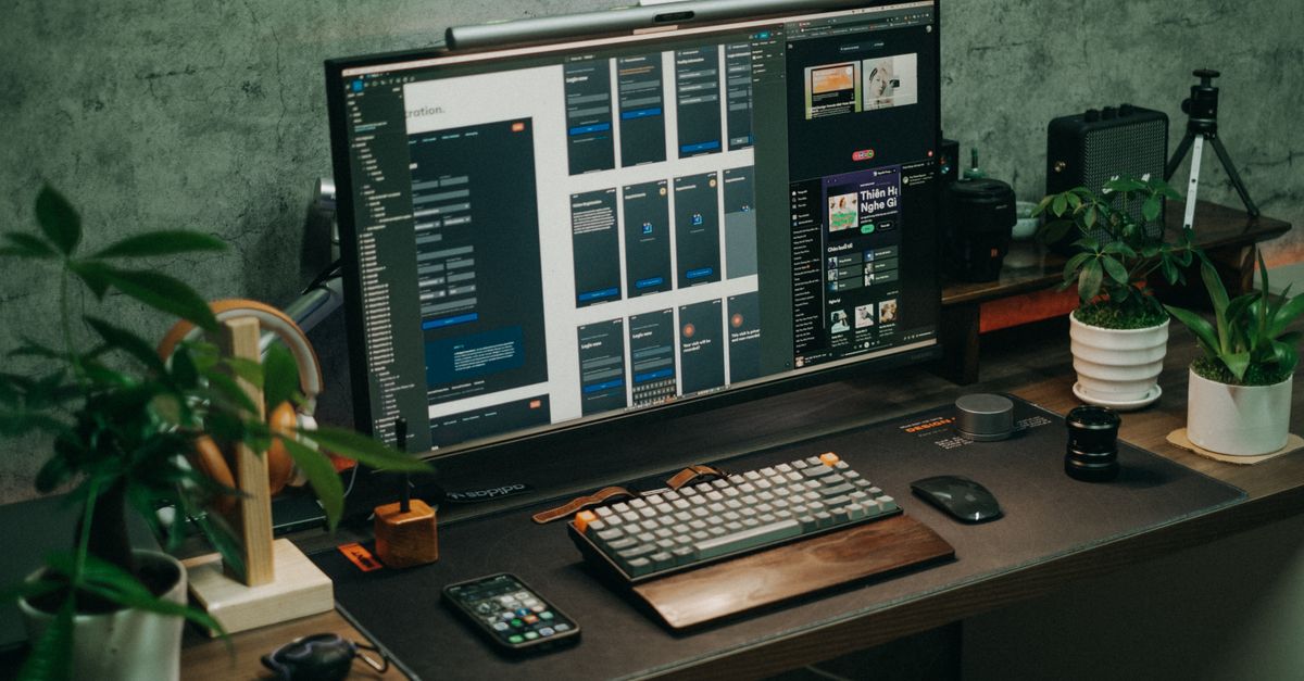 A tidy office desk featuring a computer monitor, keyboard, and plants for a modern workspace vibe.
